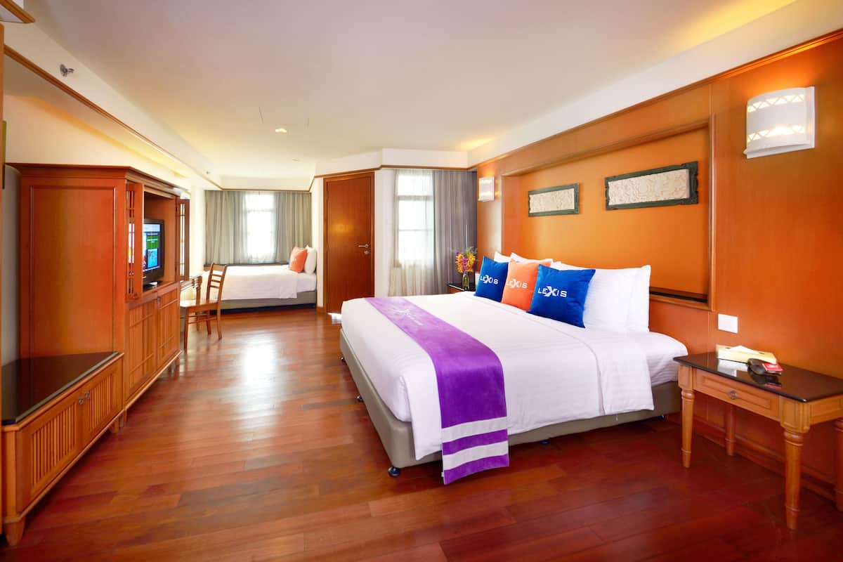A hotel room with a large bed, a television, a desk, and a wardrobe.