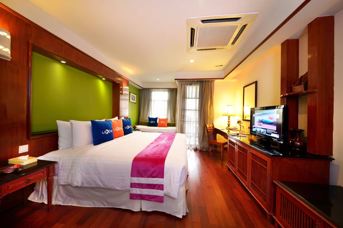 A hotel room with a large bed, a television, a desk, and a chair.
