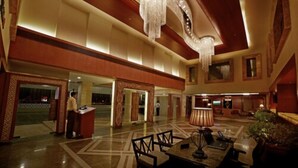A spacious lobby with a grand chandelier, a reception desk, and seating areas. - Hablis Hotel (Chennai)