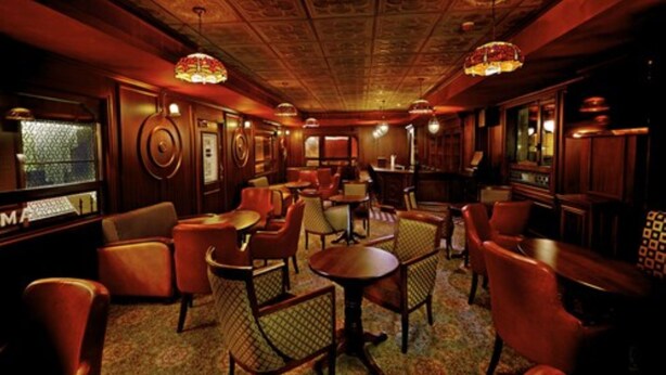 A dimly lit bar area with wooden furniture and patterned carpet. - Hablis Hotel (Chennai)