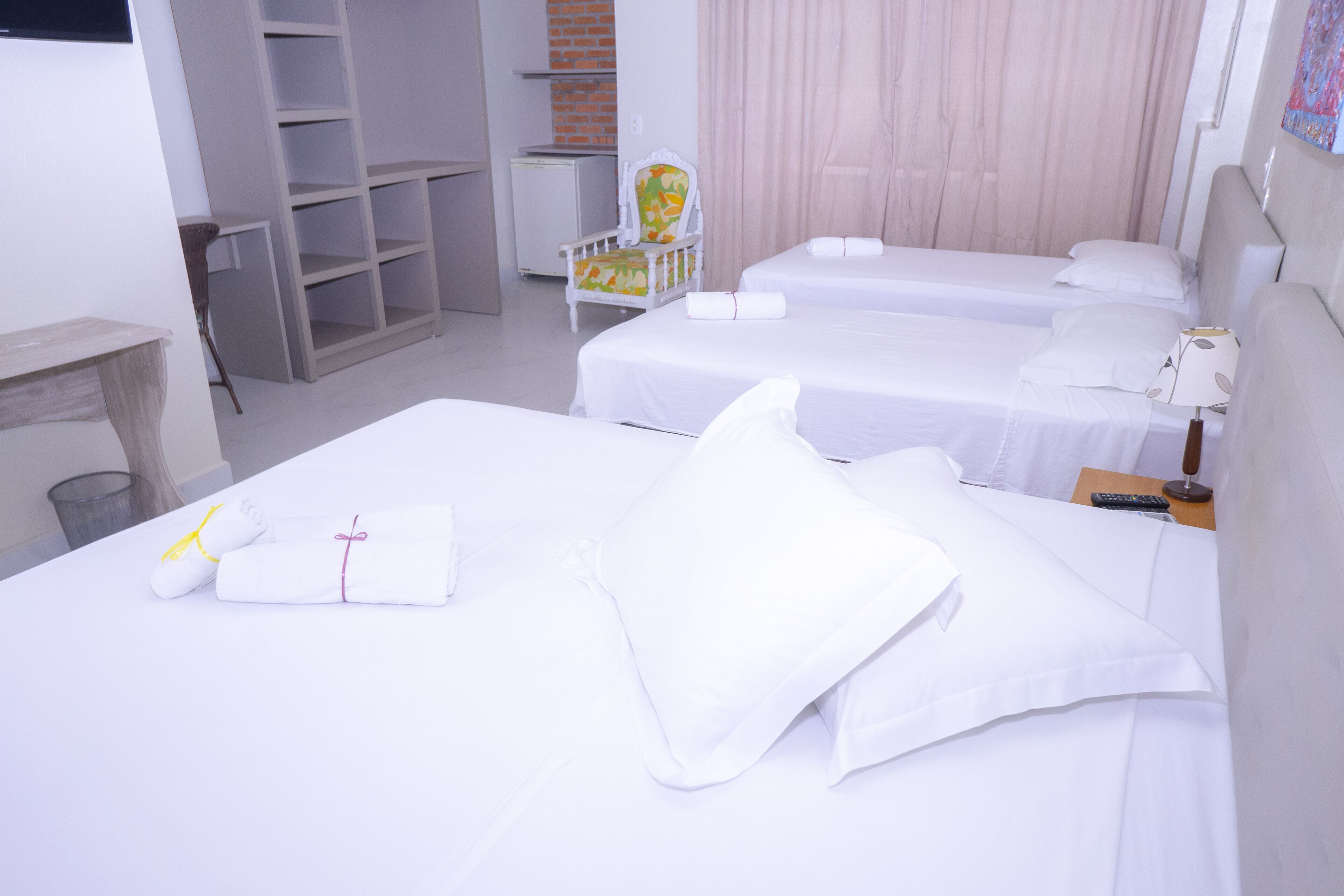 A hotel room with two beds, a chair, a desk, and a wardrobe.