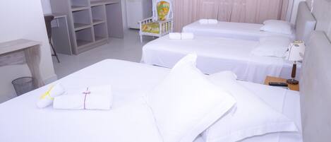 A hotel room with two beds, a chair, a desk, and a wardrobe.
