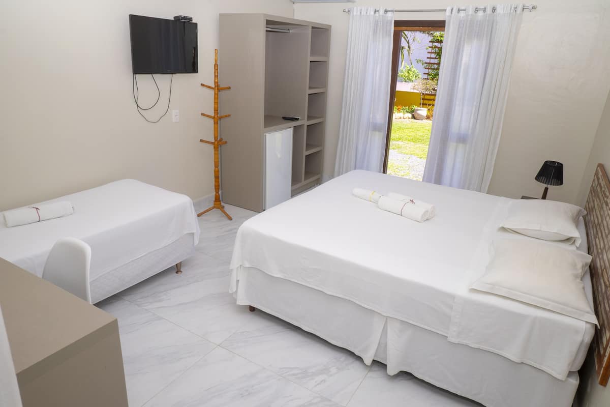 Ein Hotelzimmer mit zwei Einzelbetten, einem Schrank, einem Fernseher und Blick auf den Garten.