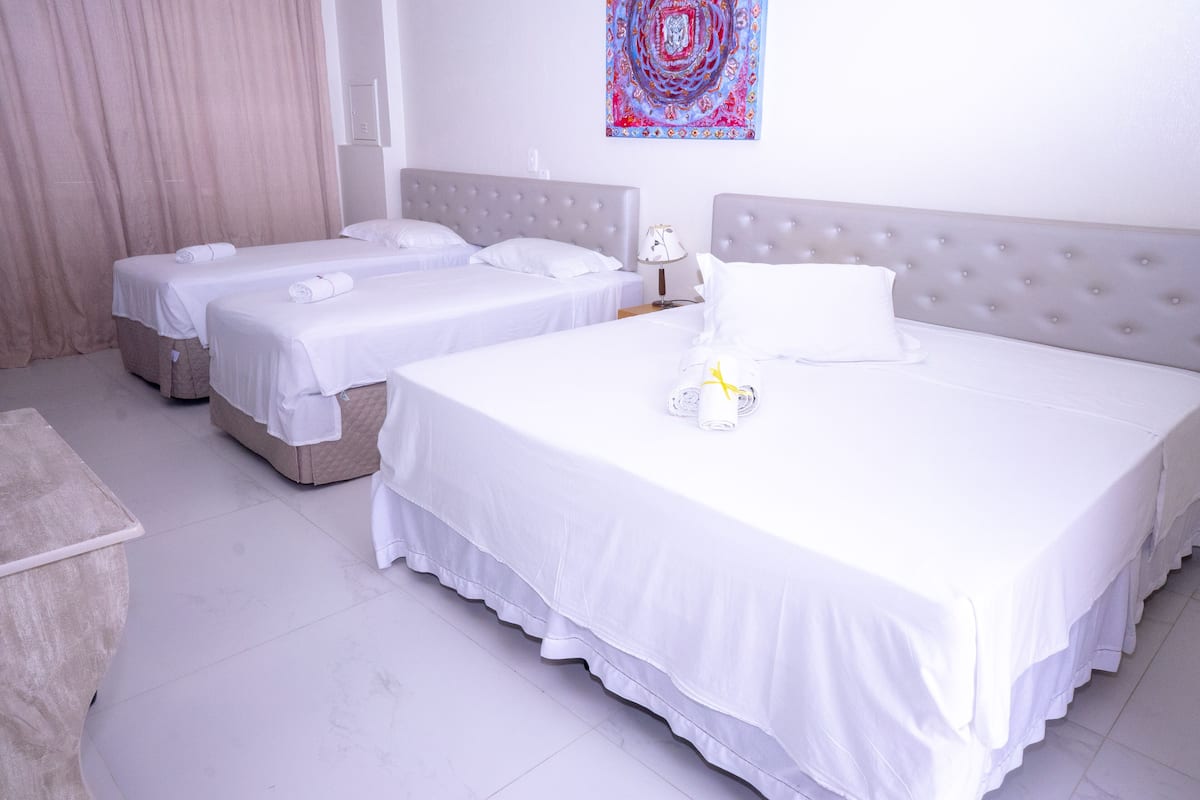 Ein Hotelzimmer mit zwei Einzelbetten, einem großen Bett und einer kleinen Schlafcouch.