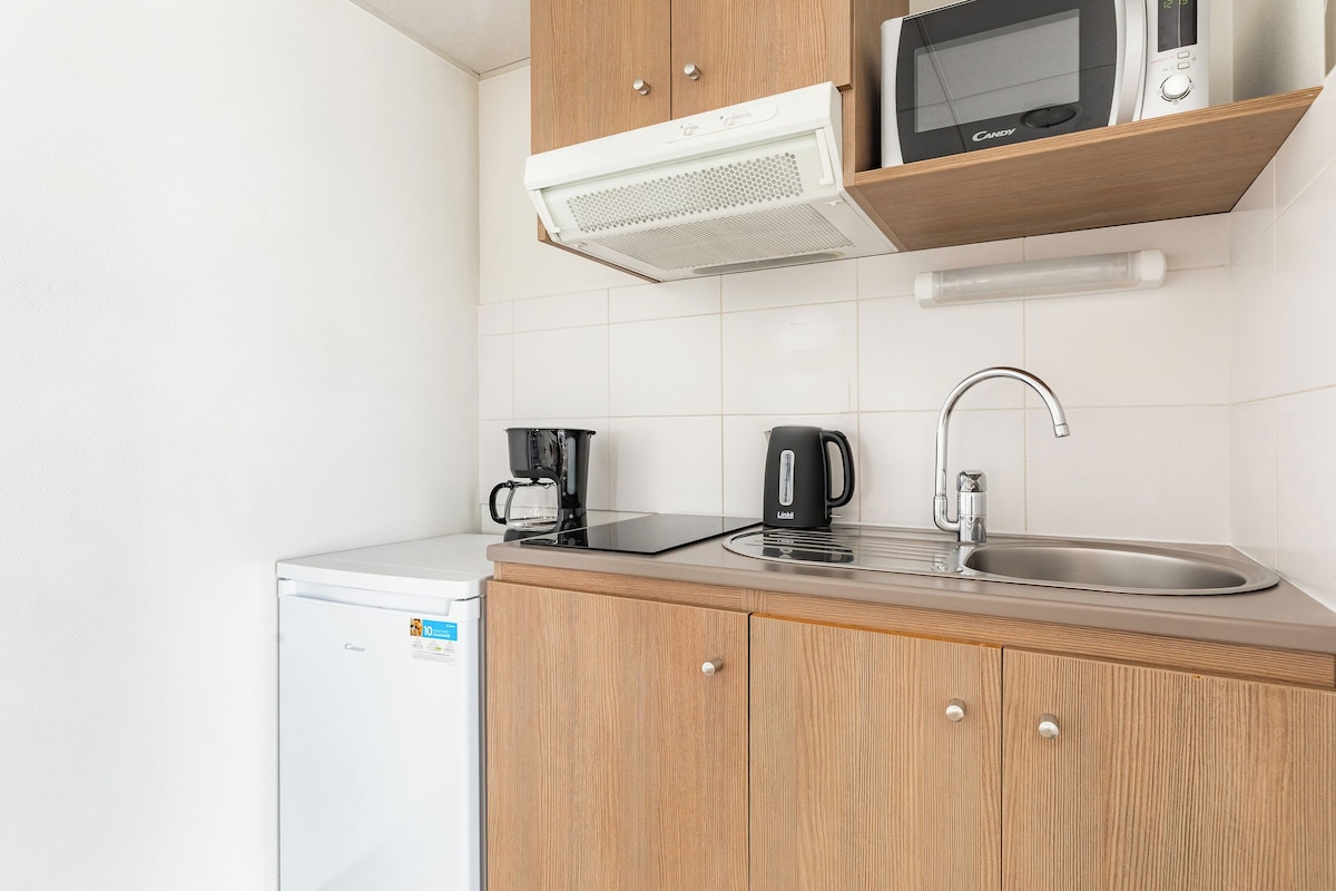 Una cocina compacta con microondas, cafetera y lavabo.