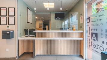Een modern ontworpen receptiebalie, met ingelijste certificaten aan de muur en een digitaal scherm erboven.
