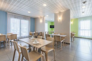 Un comedor moderno con mesas, sillas, un televisor de pantalla plana y una pared de acento verde.