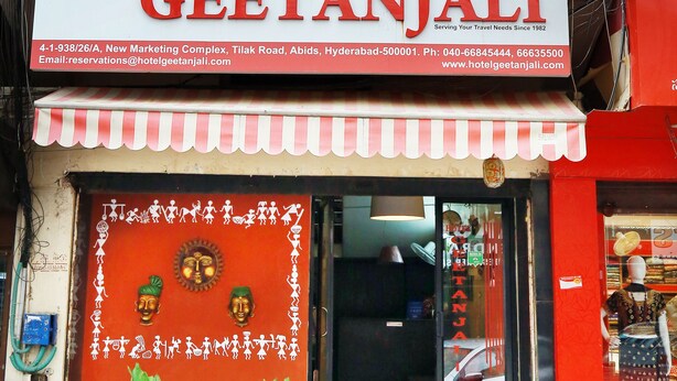 A hotel sign with contact details and a storefront with a red awning and decorative elements. - Hotel Geetanjali (Hyderabad)