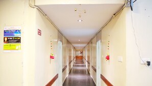 A long, narrow hallway with glass doors on both sides, a marble floor, and a chandelier on the ceiling. - Hotel Geetanjali (Hyderabad)