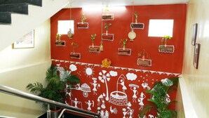 A staircase with a red wall featuring white decorative patterns and hanging planters. - Hotel Geetanjali (Hyderabad)