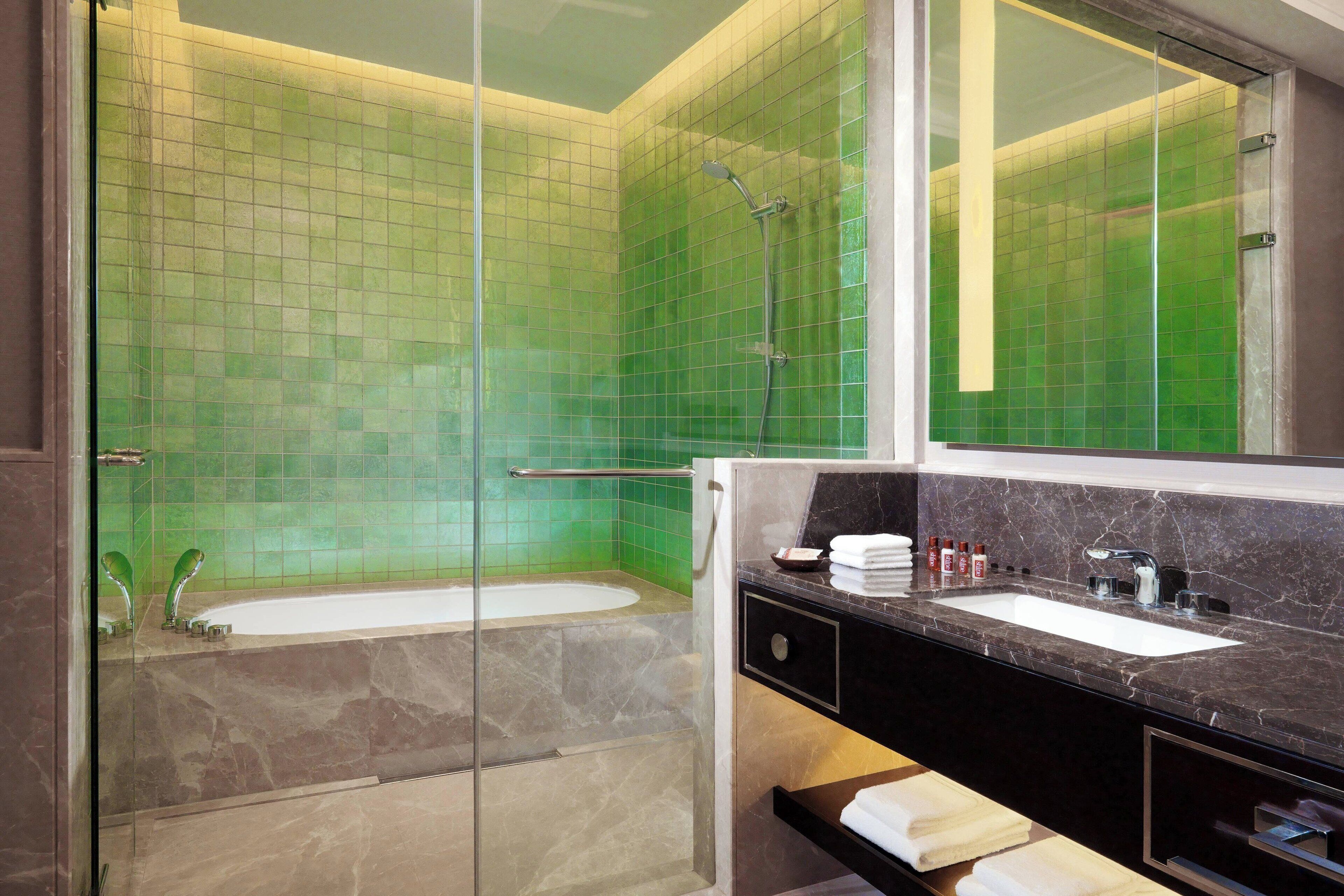 A bathroom with a glass-enclosed shower, a bathtub, and a vanity with a sink and mirror.