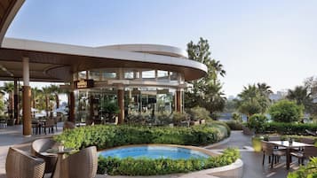 Un área exterior moderna con piscina, mobiliario y un restaurante llamado "Brooks".