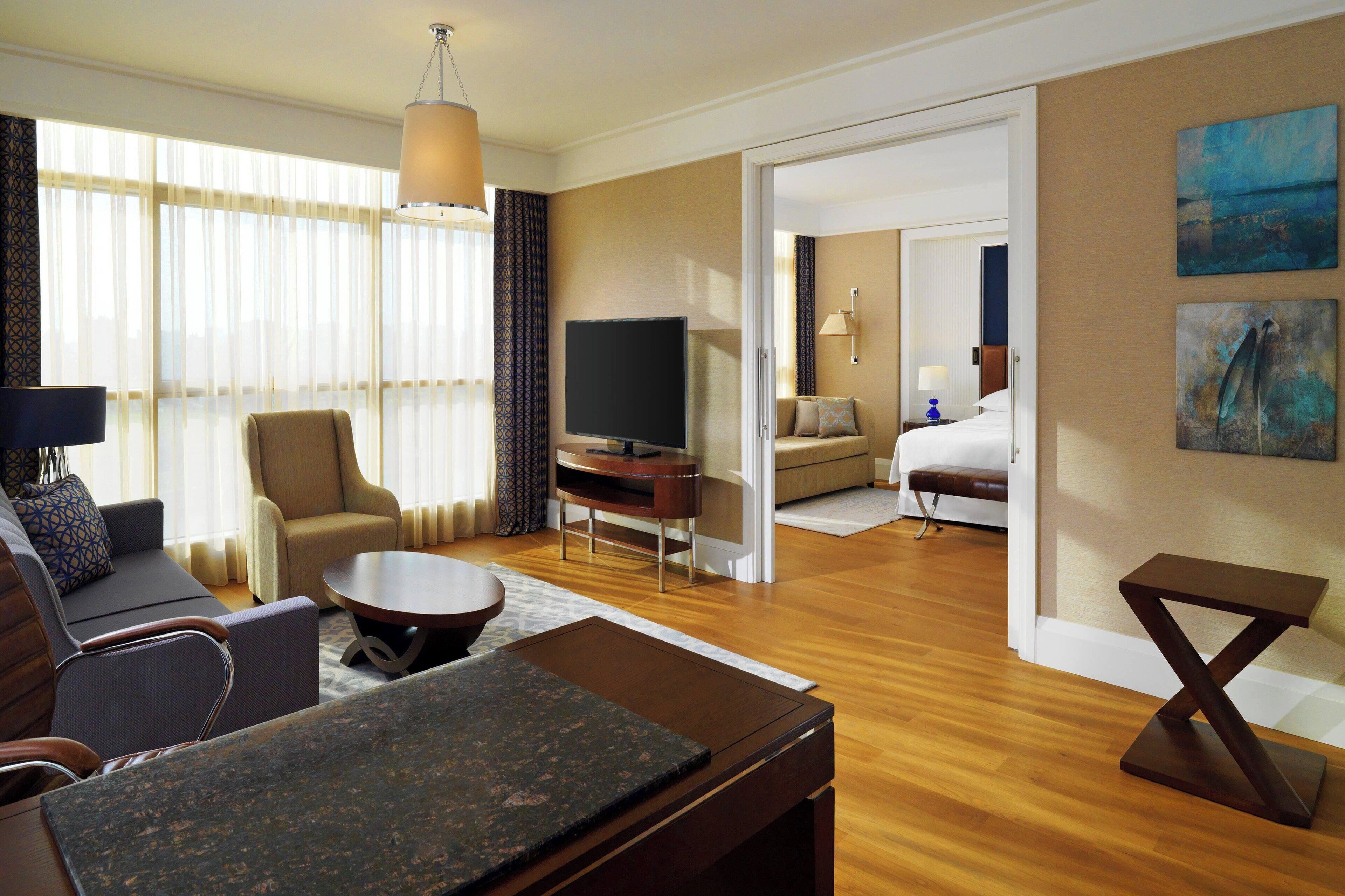 Une chambre d’hôtel équipée d’un canapé, d’un fauteuil, d’une table basse, d’un téléviseur à écran plat et d’un lit.