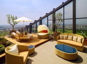 A rooftop terrace with wicker furniture, a glass table, and a view of the cityscape. - Sheraton Grand Adana (Adana)