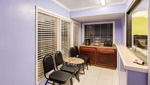 A compact kitchen with a dining area, featuring a round table, black chairs, and a wooden counter.