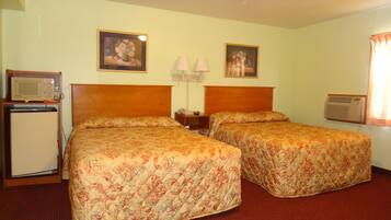 A hotel room with two beds, a small refrigerator, a microwave, a lamp, and an air conditioner.