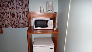 Une petite cuisine équipée comprenant un four à micro-ondes et un petit réfrigérateur, le tout posé sur un meuble en bois.