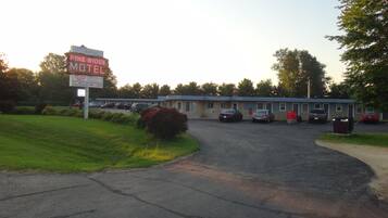 Pine Ridge Motel met een parkeerplaats, een gebouw met een blauw dak en een bord met daop advertentie voor lage prijzen en zakelijke gasten.