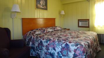A hotel room with a floral bedspread, a wooden headboard, two bedside lamps, and a framed picture on the wall.