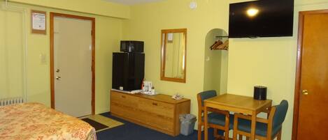 A hotel room with two beds, a wooden dresser, a desk with a chair, a television, and a mirror.