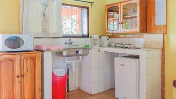 A compact kitchen with a microwave, sink, coffee maker, and a small refrigerator.