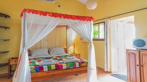 A bed with a colorful quilt, a bedside table, a lamp, and a television on a wooden cabinet.