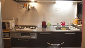 Una cocina compacta con estufa a gas, microondas y pileta.