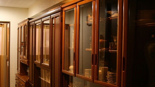 Una cocina con armarios de madera y estantes de vidrio que exhiben vajilla.