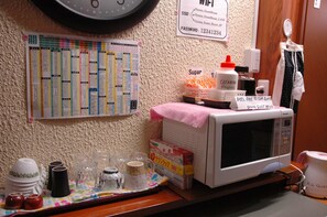 Un microondas, una bandeja con tazas y un calendario, y un cartel con los detalles de la red WiFi.