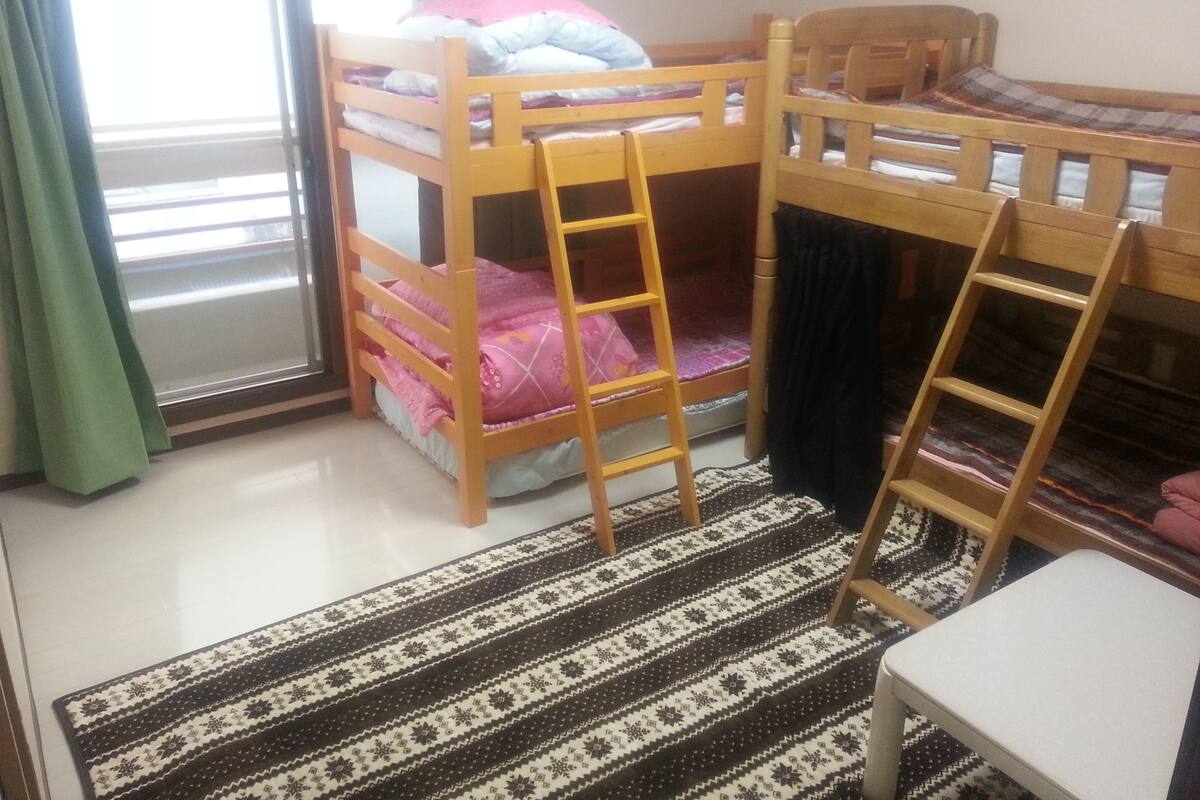 Una habitación con dos literas, una mesita pequeña y un tapete estampado.
