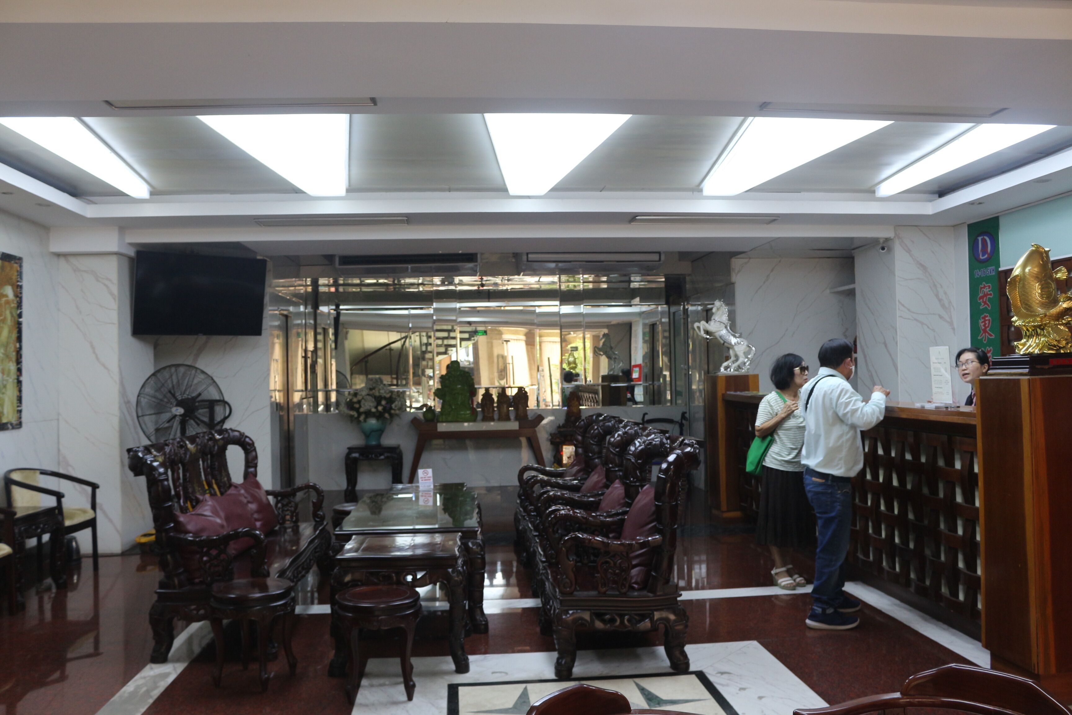 Un vestíbulo con muebles decorativos, un mostrador de recepción y un espejo grande.