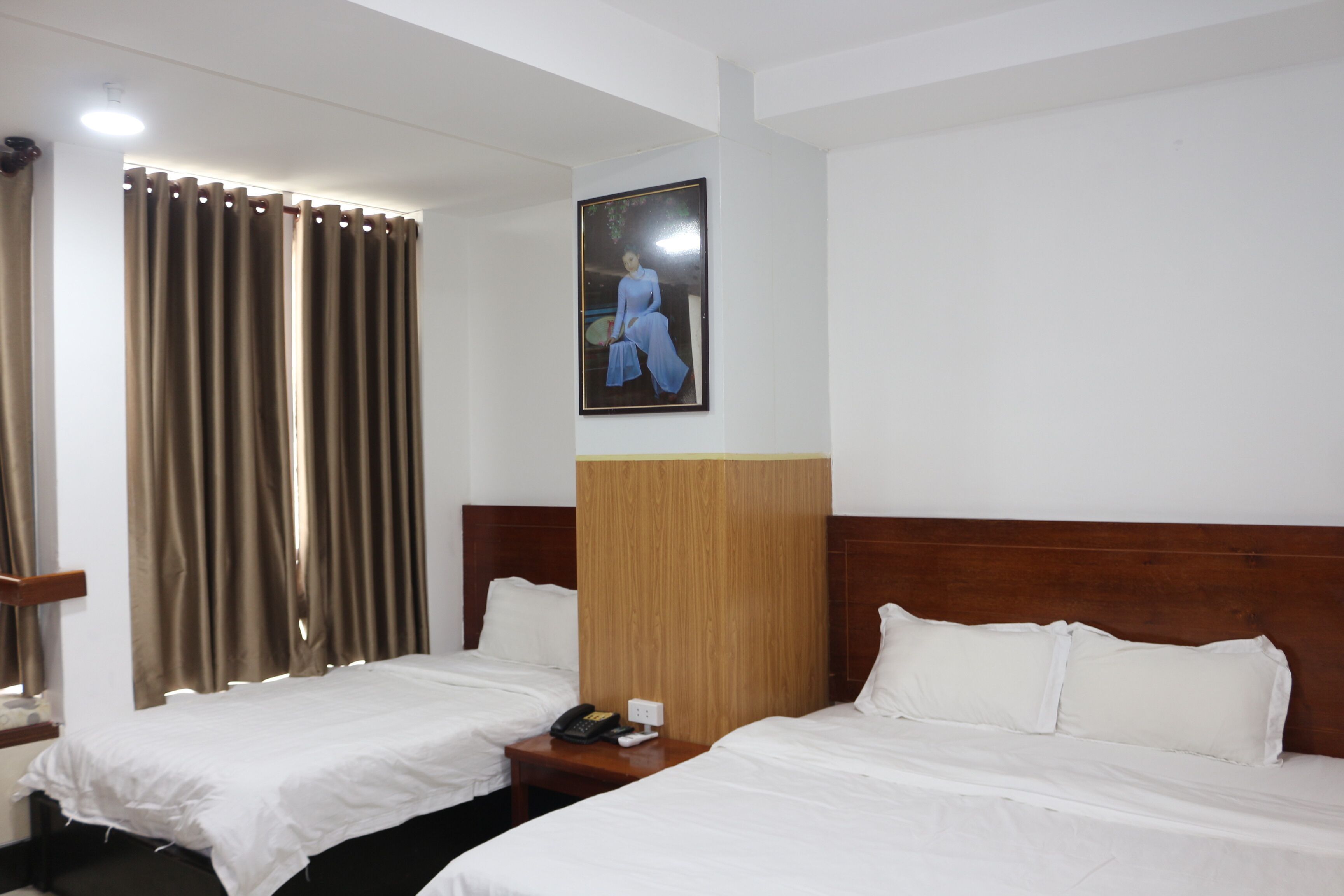 Habitación de hotel con dos camas, cabecero de madera, un cuadro en la pared y un teléfono en la mesita de noche.