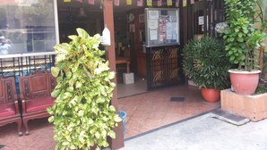 A restaurant entrance with a signboard, potted plants, and a wooden bench. - Anggerik Lodging Hotel (George Town)