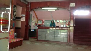 A reception area with a tiled floor, a reception desk, a clock, and a wall-mounted air conditioning unit. - Hosaga Biz Hotel (KELANTAN)