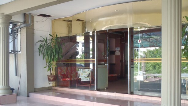 A building entrance with a glass door, a potted plant, and a tiled floor. - Hosaga Biz Hotel (KELANTAN)