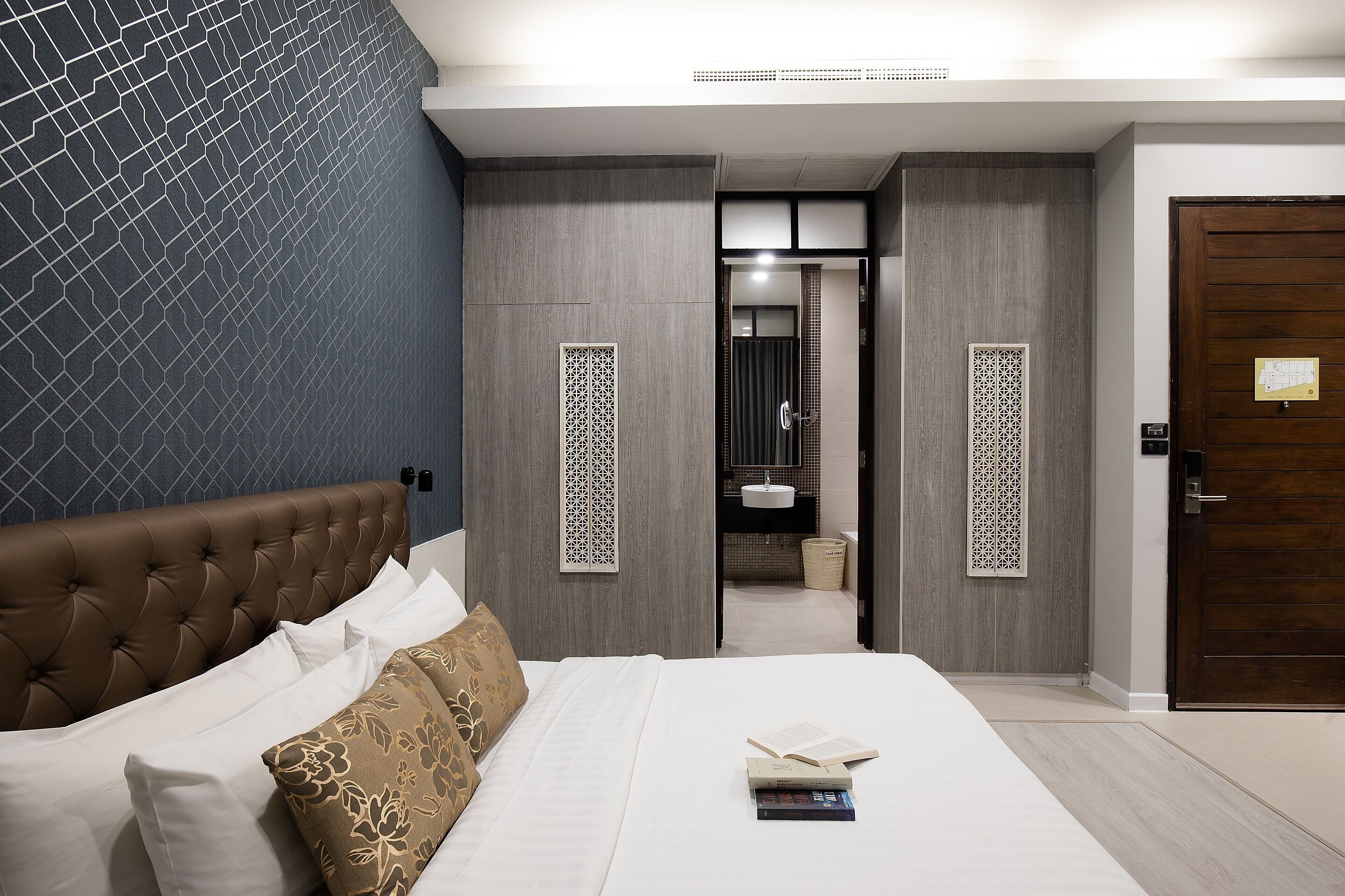 Hotelkamer met een bed, nachtkastje, badkamer met wastafel en spiegel, en een deur met een kaart.