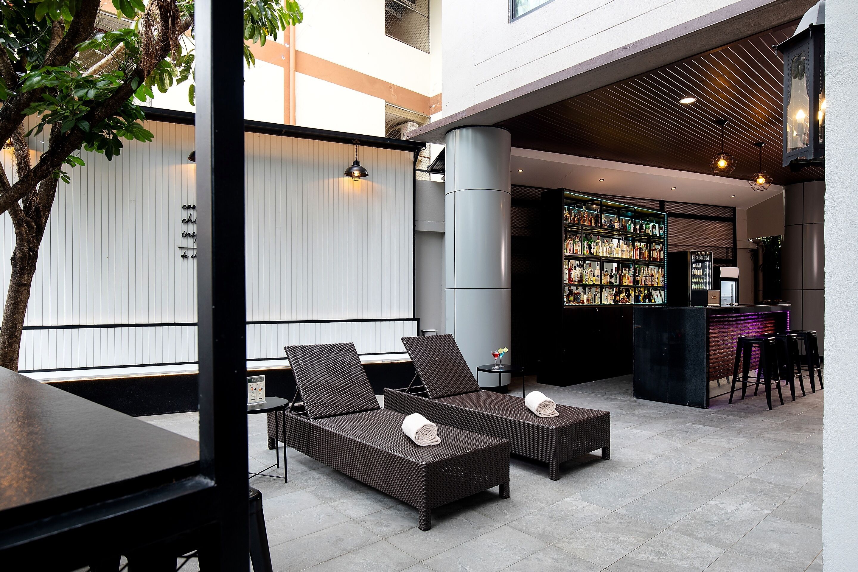 An outdoor seating area with wicker furniture and a bar with a variety of bottles.