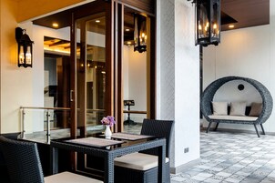 A modern outdoor seating area with wicker furniture, a glass partition, and ambient lighting.