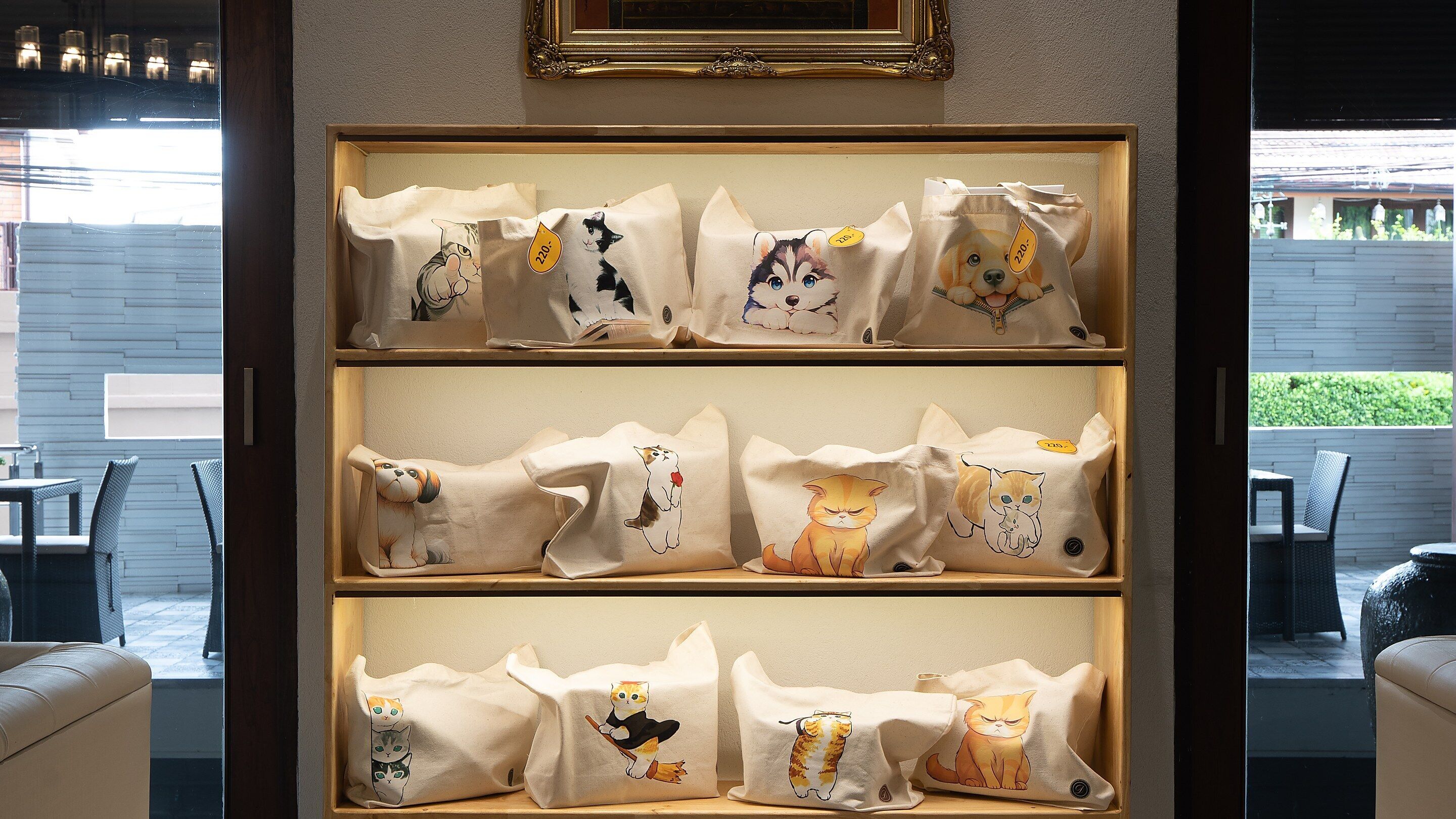 A display of bags with cat designs in a wooden frame.