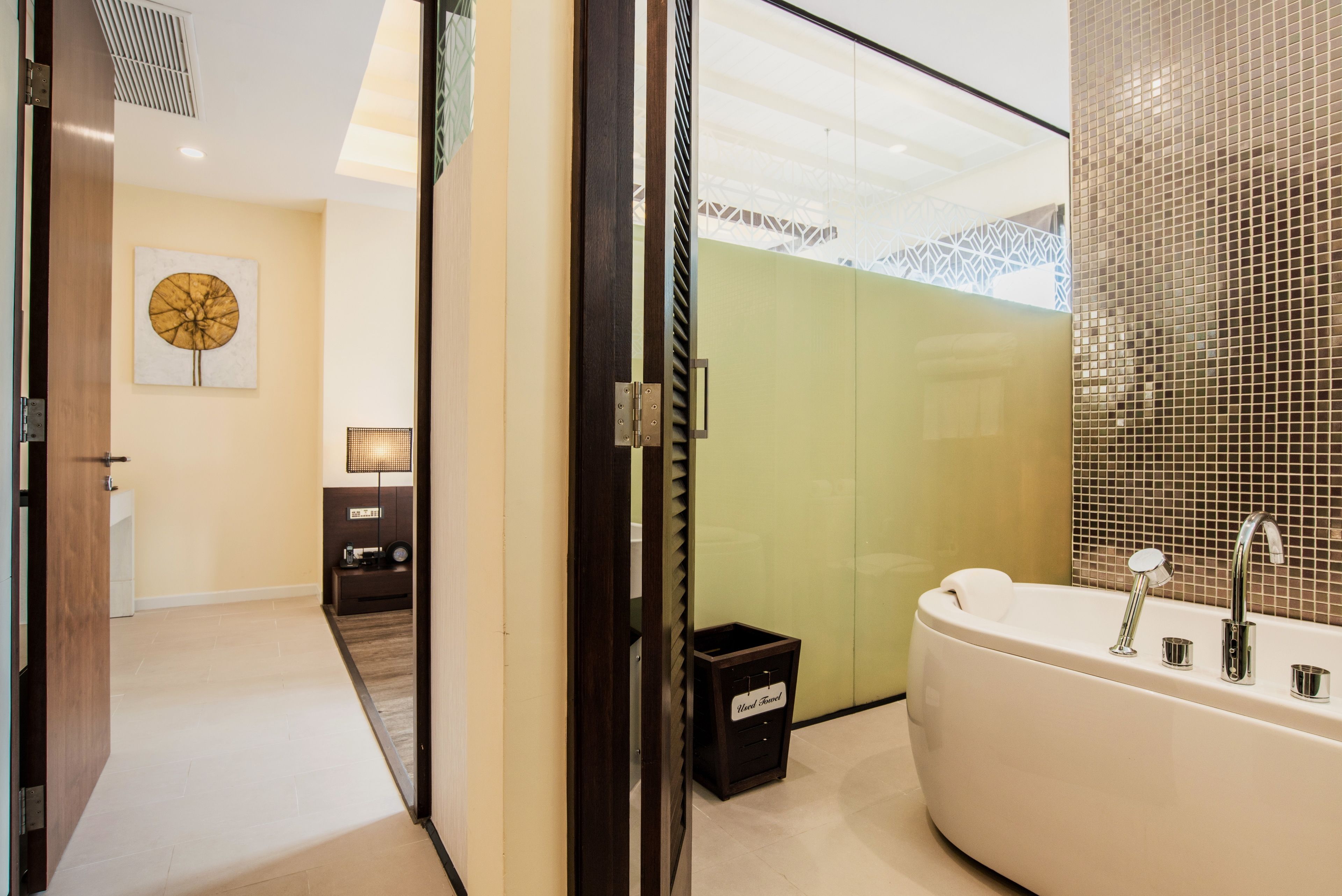 A modern bathroom with a freestanding bathtub, a towel rack, and a small trash bin.
