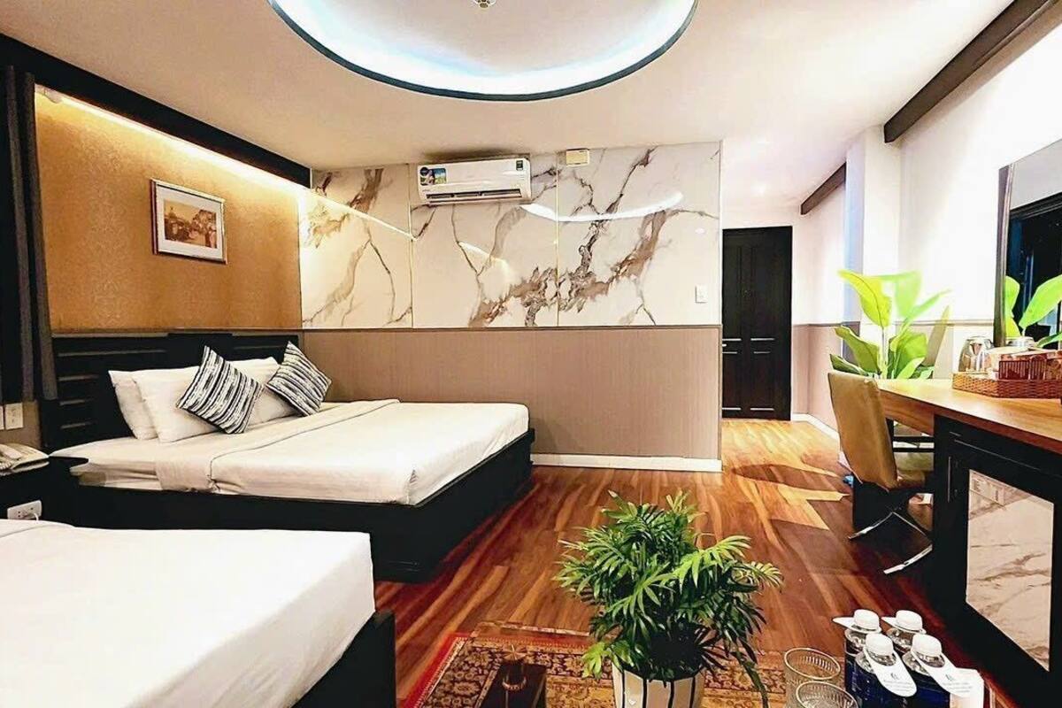 A hotel room with a bed, bedside table, TV, and a desk with a chair.
