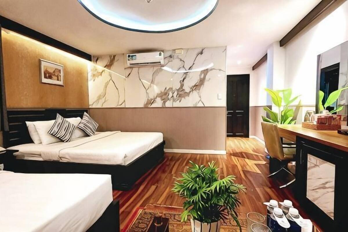 A modern hotel room with a bed, bedside table, and a large mirror.
