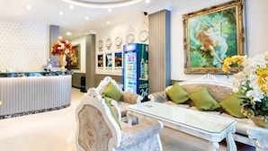 A hotel lobby with a reception desk, seating area, and a large painting on the wall. - Rosa Hotel & Spa (Ho Chi Minh City)