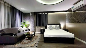 A modern hotel room with a bed, a sofa, a nightstand, and a potted plant. - Rosa Hotel & Spa (Ho Chi Minh City)