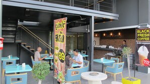 Un espace extérieur aménagé avec des tables et des chaises, un escalier et une enseigne publicitaire pour le café Black Fresh.