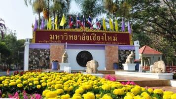 A university entrance with a stone facade, a central emblem, and a row of flags.