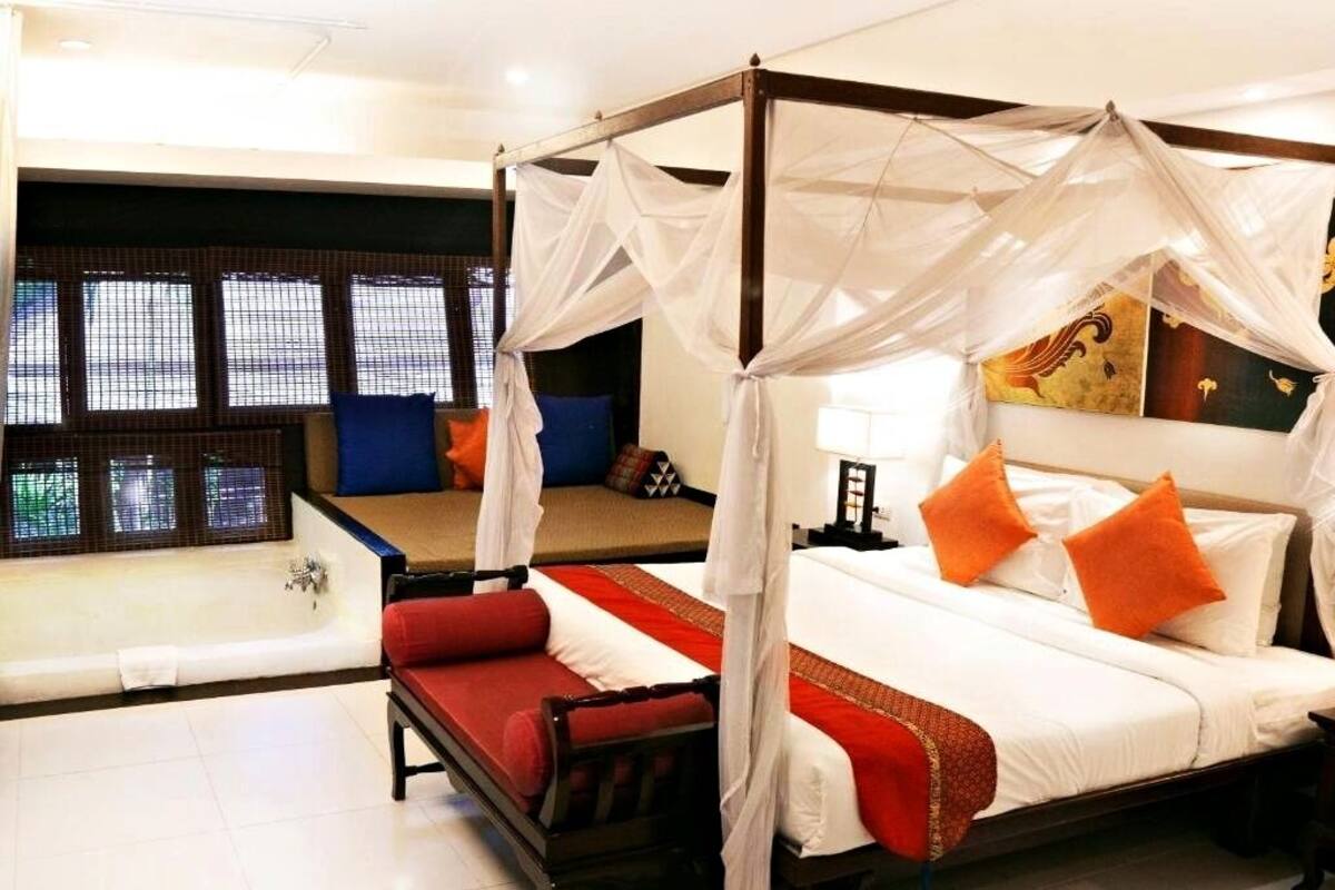 A four-poster bed with a canopy, a separate sofa, and a bathtub.