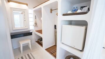 Un bany compacte i modern amb un rentapeus blanc, un mirall i prestatges per desar.