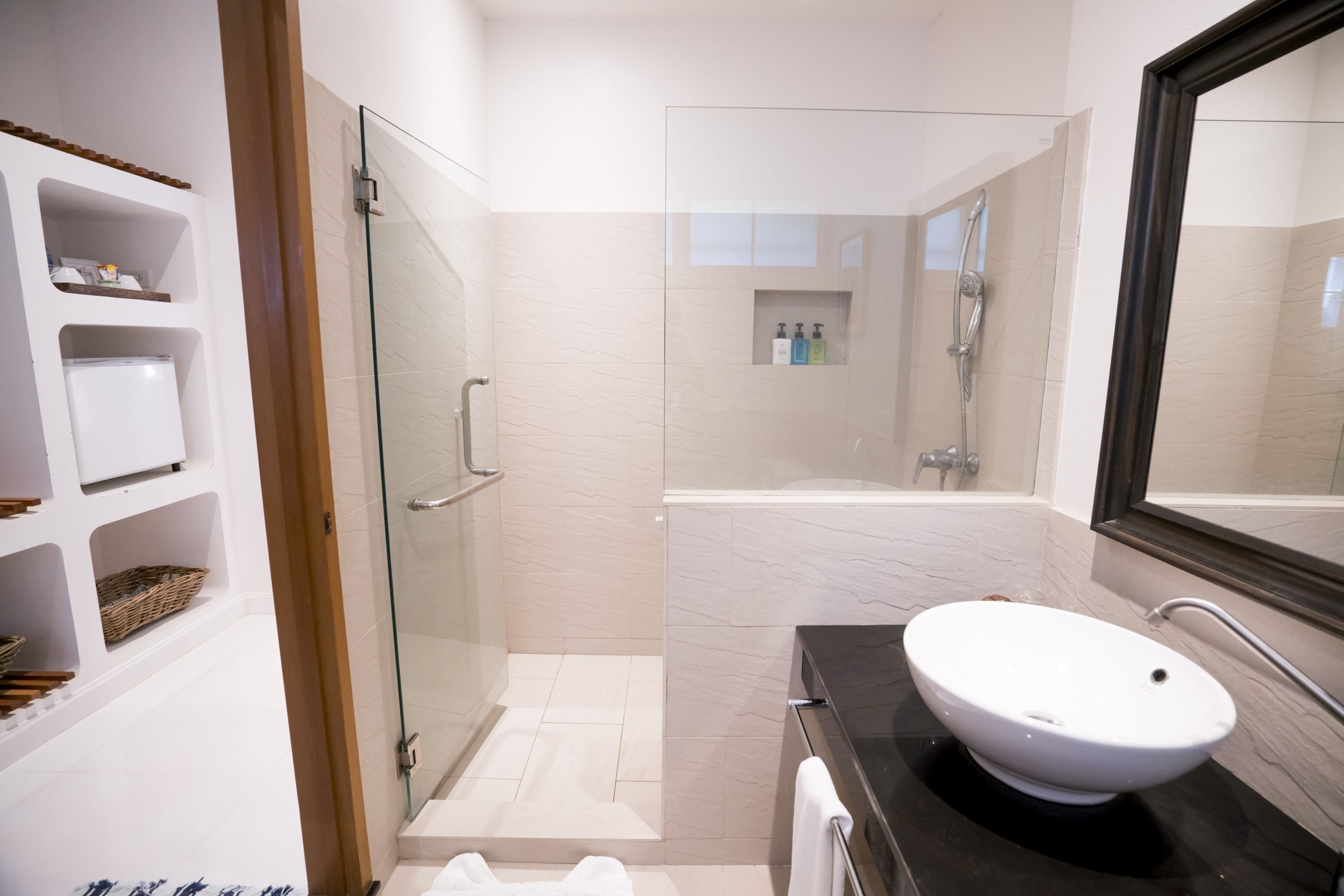 Un baño moderno con cabina de ducha de vidrio, un lavabo blanco y un espejo grande.