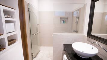 Un baño moderno con cabina de ducha de vidrio, un lavabo blanco y un espejo grande.